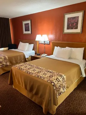 two beds in a hotel room with orange walls at Executive Inn Schenectady Downtown in Schenectady