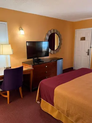 a hotel room with a bed and a desk and a television at Executive Inn Schenectady Downtown in Schenectady
