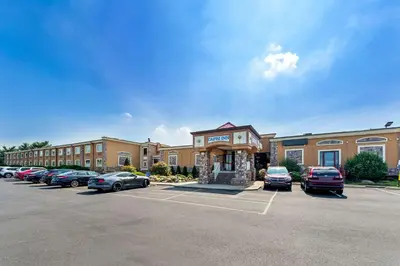 a building with cars parked in a parking lot at Rodeway Inn Capri in Little Ferry