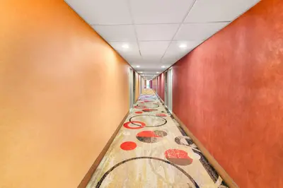a hallway with a long aisle with paintings on the wall at Rodeway Inn Capri in Little Ferry