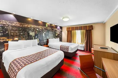a hotel room with two beds and a flat screen tv at Rodeway Inn Capri in Little Ferry