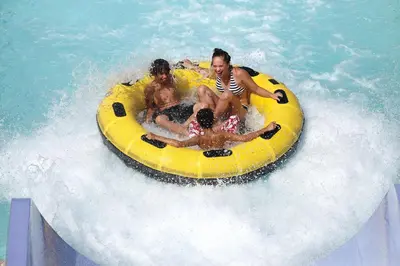 a group of people riding on a yellow raft in the water at Six Flags Great Escape Lodge & Indoor Waterpark in Queensbury