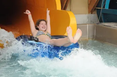 a young girl riding on a raft in a water slide at Six Flags Great Escape Lodge & Indoor Waterpark in Queensbury