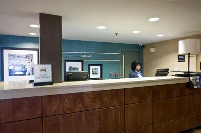 a woman standing at a counter in a waiting room at Hampton Inn by Hilton Milford in Milford