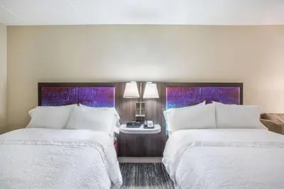 a hotel room with two beds and a table at Hampton Inn Fishkill in Fishkill