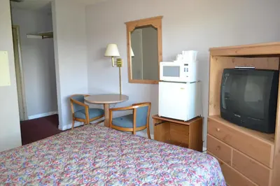 a hotel room with a bed and a tv and a table at Latham Inn in Latham