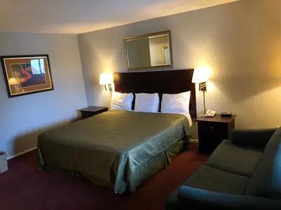a hotel room with a bed and a chair at Latham Inn in Latham