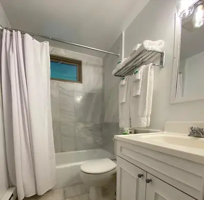 a white bathroom with a toilet and a sink at Catskill Seasons Inn in Shandaken