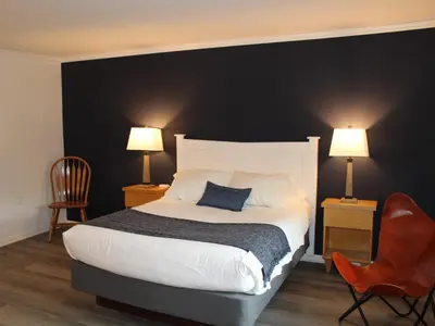 a bedroom with a large bed with two lamps and two chairs at Catskill Seasons Inn in Shandaken