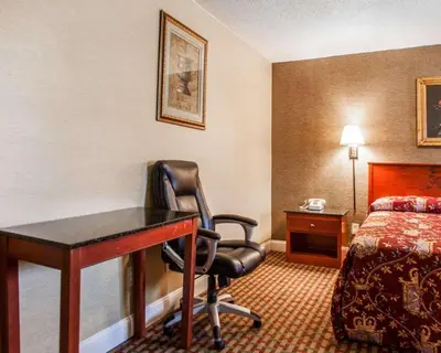 a hotel room with a desk and a bed at Rodeway Inn Paterson Great Falls Park Area in Paterson