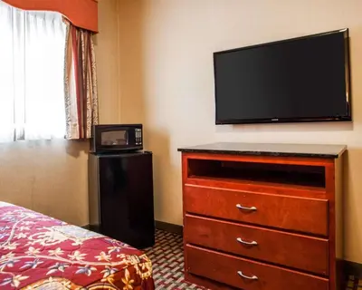a bedroom with a dresser with a flat screen tv at Rodeway Inn Paterson Great Falls Park Area in Paterson