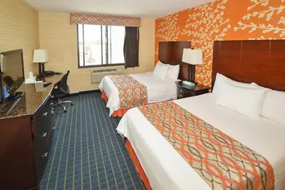 a hotel room with two beds and a desk at Corona Hotel New York - LaGuardia Airport in Queens