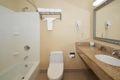 a bathroom with a toilet and a sink and a tub at Corona Hotel New York - LaGuardia Airport in Queens