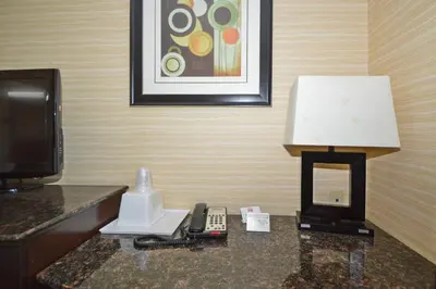 a hotel room with a lamp and a phone on a table at Corona Hotel New York - LaGuardia Airport in Queens
