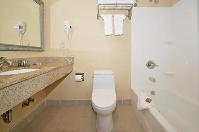 a bathroom with a toilet and a sink and a tub at Corona Hotel New York - LaGuardia Airport in Queens