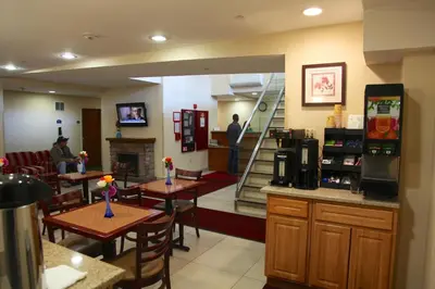 a restaurant with tables and a fireplace and a man standing in the room at Corona Hotel New York - LaGuardia Airport in Queens