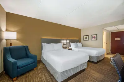 a hotel room with two beds and a blue chair at Comfort Inn & Suites East Hartford - Hartford in East Hartford