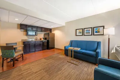 a living room with a blue couch and a kitchen at Comfort Inn & Suites East Hartford - Hartford in East Hartford