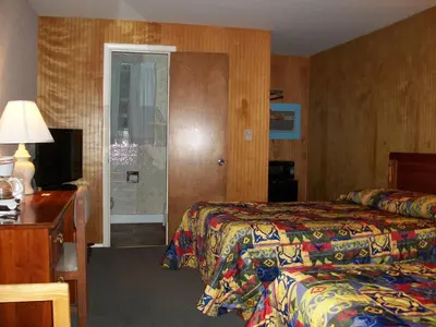 a hotel room with two beds and a desk and a television at Mohican Motel in Cooperstown