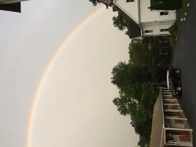 a rainbow in the sky with a building at Mohican Motel in Cooperstown