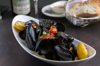 a bowl of mussels on a table with a plate of bread at Four Points by Sheraton Manhattan SoHo Village in New York