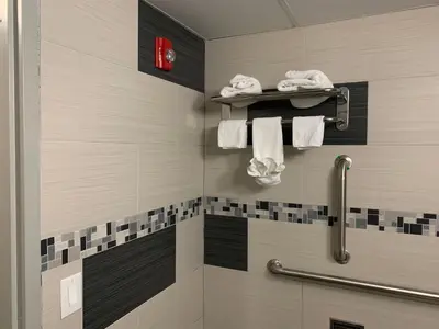 a bathroom with a shower with towels on a shelf at Red Carpet Inn Elmwood in Elmwood Park