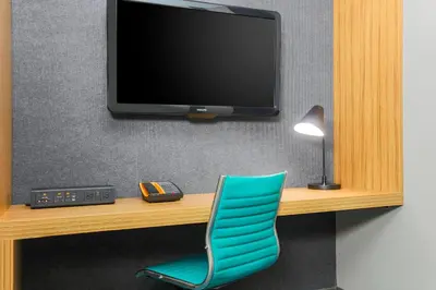 a room with a desk with a tv and a blue chair at Aloft Harlem in New York