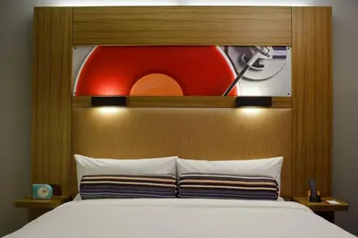 a bed with a wooden headboard with a picture above it at Aloft Harlem in New York