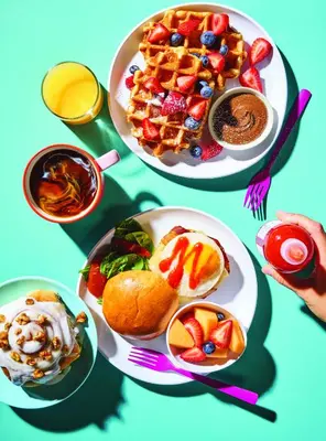 a table with two plates of breakfast foods and waffles at Aloft Harlem in New York