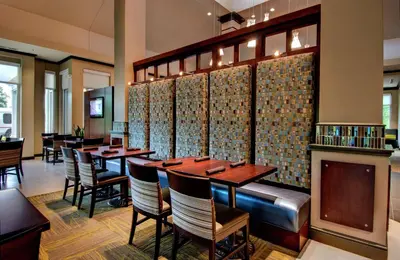 a restaurant with tables and chairs and a fireplace at Hilton Garden Inn Albany Airport in Albany