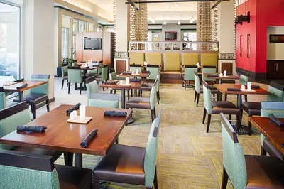a dining room with wooden tables and chairs at Hilton Garden Inn Albany Airport in Albany