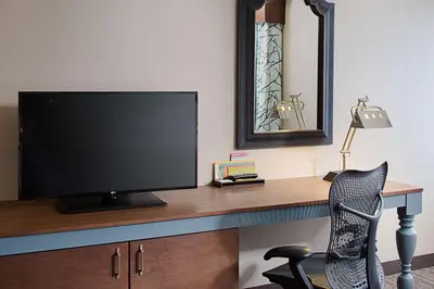 a desk with a television and a chair in a room at Hilton Garden Inn Albany Airport in Albany