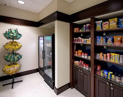 a store aisle with a refrigerator and shelves of food at Hampton Inn Schenectady Downtown in Schenectady