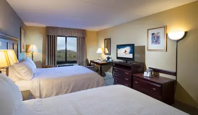 a hotel room with two beds and a flat screen tv at Hampton Inn Bennington in Bennington