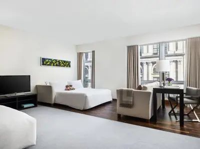 a white living room with a couch and a table at The Langham, New York, Fifth Avenue in New York