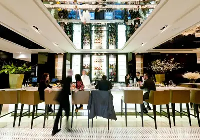 a group of people sitting at tables in a restaurant at The Langham, New York, Fifth Avenue in New York