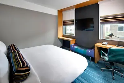 a hotel room with a bed and a desk with a computer at Aloft New York Brooklyn in Brooklyn