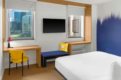 a bedroom with a bed and a desk with a tv at Aloft New York Brooklyn in Brooklyn