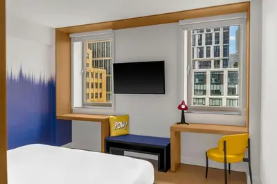 a bedroom with a bed and a desk and a bed and window at Aloft New York Brooklyn in Brooklyn