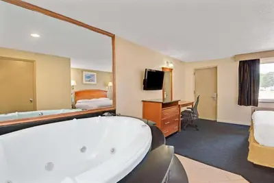 a hotel room with a bath tub and a bedroom at Super 8 by Wyndham Milford/New Haven in Milford