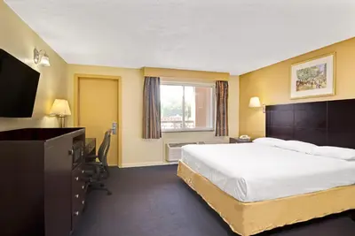 a hotel room with a bed and a television at Super 8 by Wyndham Milford/New Haven in Milford