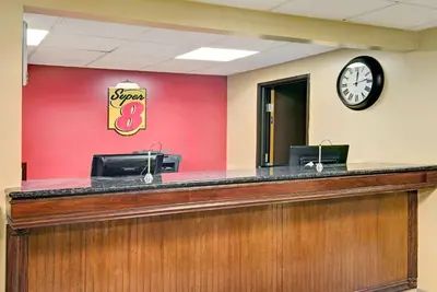 a reception desk with a clock on a red wall at Super 8 by Wyndham Stamford/New York City Area in Stamford