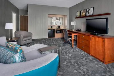 a hotel room with a couch and a desk with a television at Courtyard Newark Liberty International Airport in Newark