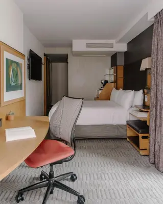 a hotel room with a bed and a desk and a table at The Jewel Hotel, New York in New York