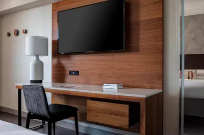 a room with a desk with a television on a wall at New York LaGuardia Airport Marriott in Queens