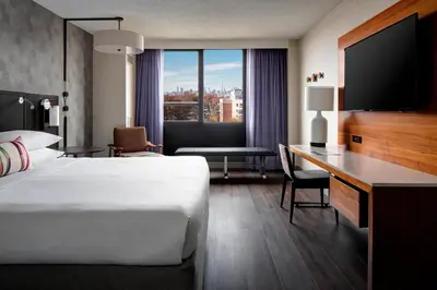 a hotel room with a bed and a desk with a television at New York LaGuardia Airport Marriott in Queens