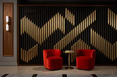 two red chairs in front of a wall with gold bars at The Opus Westchester, Autograph Collection in White Plains