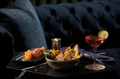 a table with a plate of food and a glass of wine at The Opus Westchester, Autograph Collection in White Plains