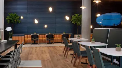 a restaurant with tables and chairs and a blue wall at The Opus Westchester, Autograph Collection in White Plains