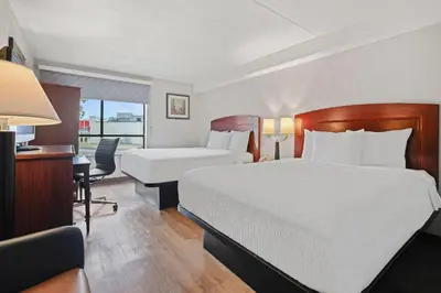 a hotel room with two beds and a desk at Days Inn by Wyndham Utica in Utica
